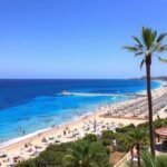 Ibiza tengerparti látkép napernyőkkel és pálmákkal