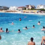 Ciprus tengerpartján úszó emberek a nyári napsütésben.