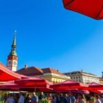 Piros napernyők a Zágráb Dolac piacon friss termékekkel.