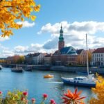 Rostock városképe ősszel, sárga levelekkel és hajókkal a folyón.