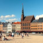 Lübeck tengerparti városkép a napfényben, látogatók a fövenyen.