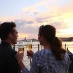 Pár néz a naplementére Velencében egy pohár Proseccóval.
