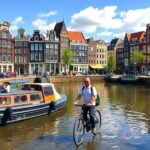 Ember kerékpározik Amszterdam csatornáján, háttérben híres épületek.