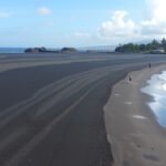Limbé Down Beach fekete vulkáni homokja és pálmafái.