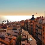 Cádiz városának panorámája, aranyló tengerparttal és ódon épületekkel.