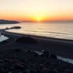 Naplemente Kamari fekete lávahomokos tengerpartján Szantorinón.