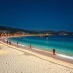 Kallithea strandja Halkidikiben éjjel, csillogó vízzel és pálmákkal