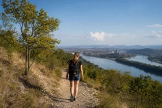 Nő túrázik a Strázsa-hegy tanösvényén, gyönyörű panorámával Esztergomra.