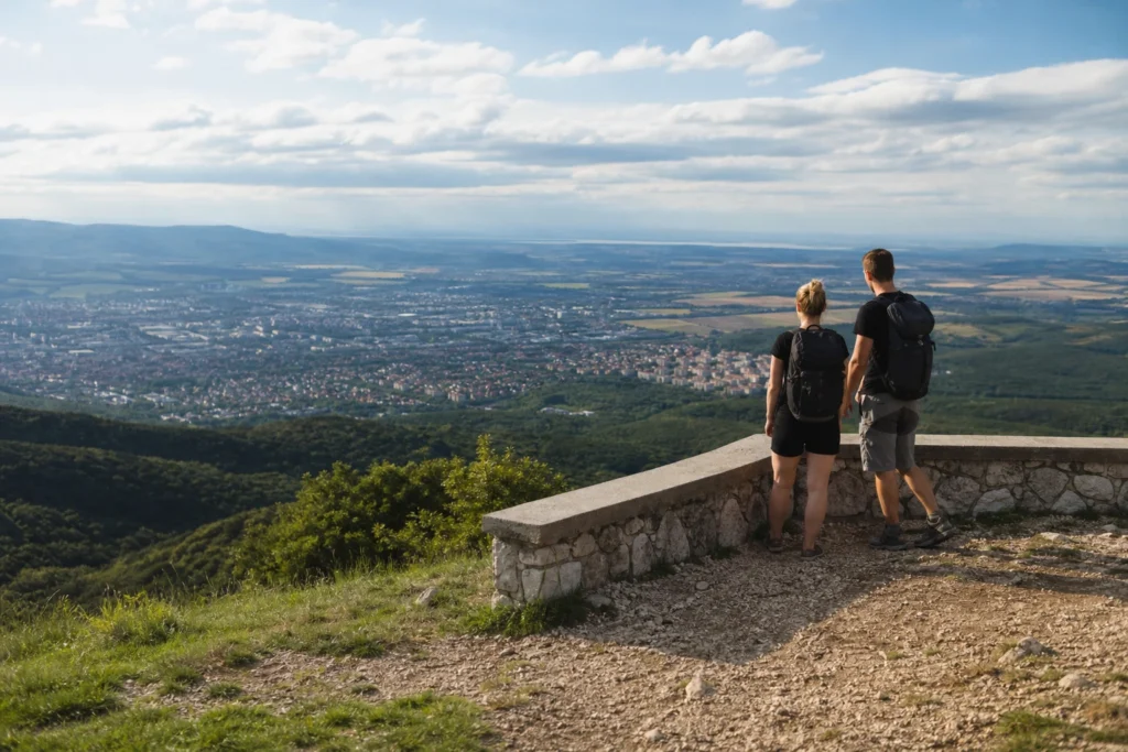 Pár sétál a Mecsek-hegység panorámáján, csodálva a kilátást.